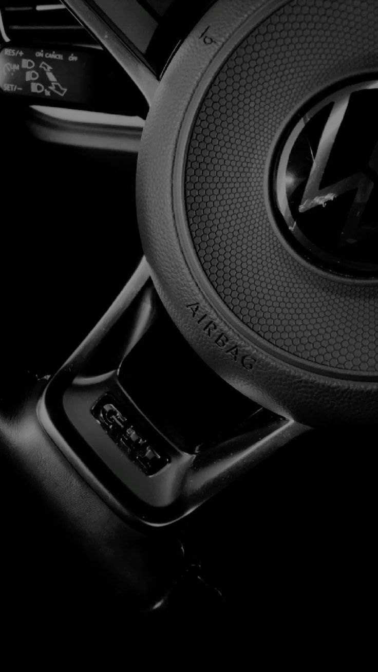 Close-up of GTI steering wheel with airbag text and textured grip in a premium car interior.
